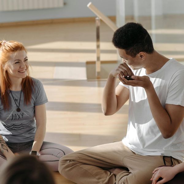 Group of diverse people sitting on yoga mats in a bright studio.